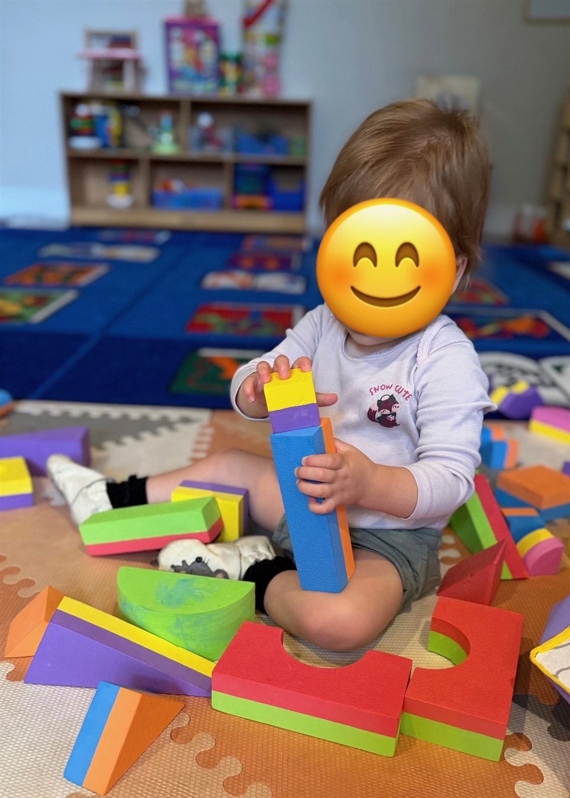 A young toddler concentrating on stacking colorful foam blocks on a play mat
