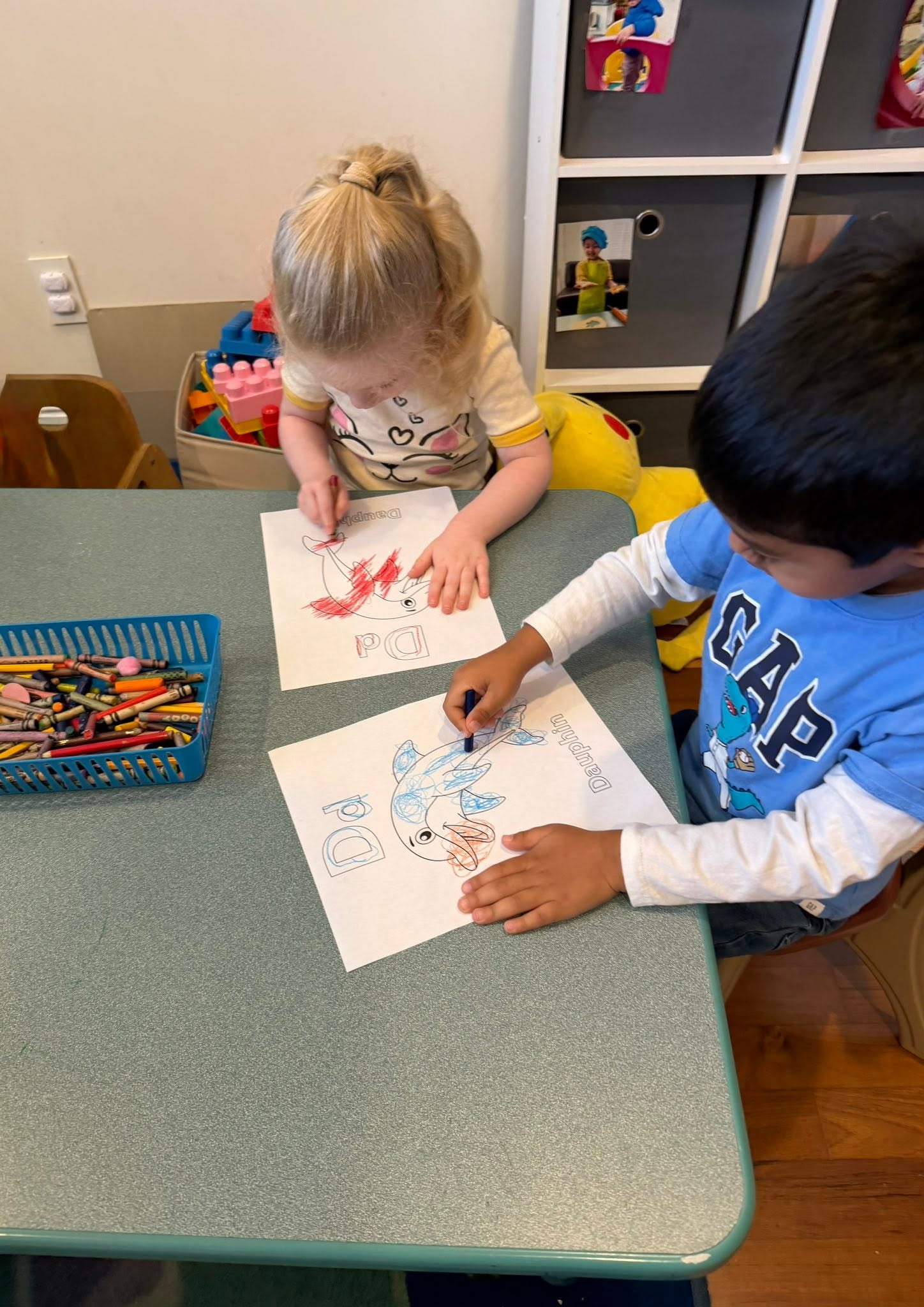 Two children coloring dolphin worksheets labeled with the French word Dauphin