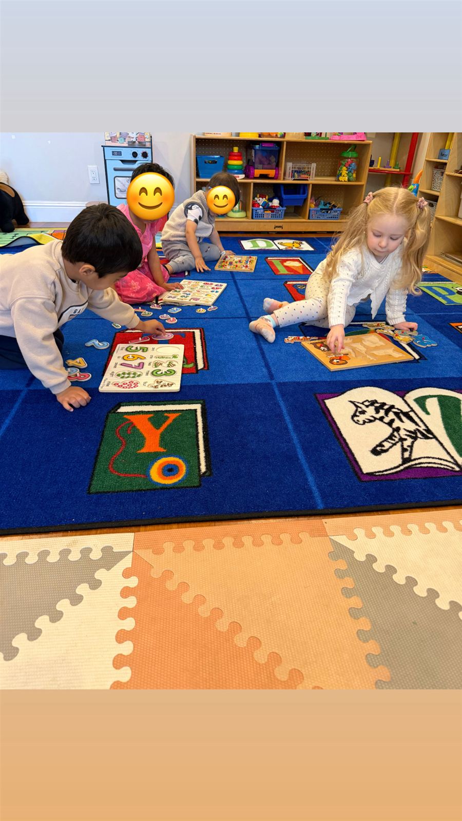 Children solving number and alphabet puzzles on the classroom rug