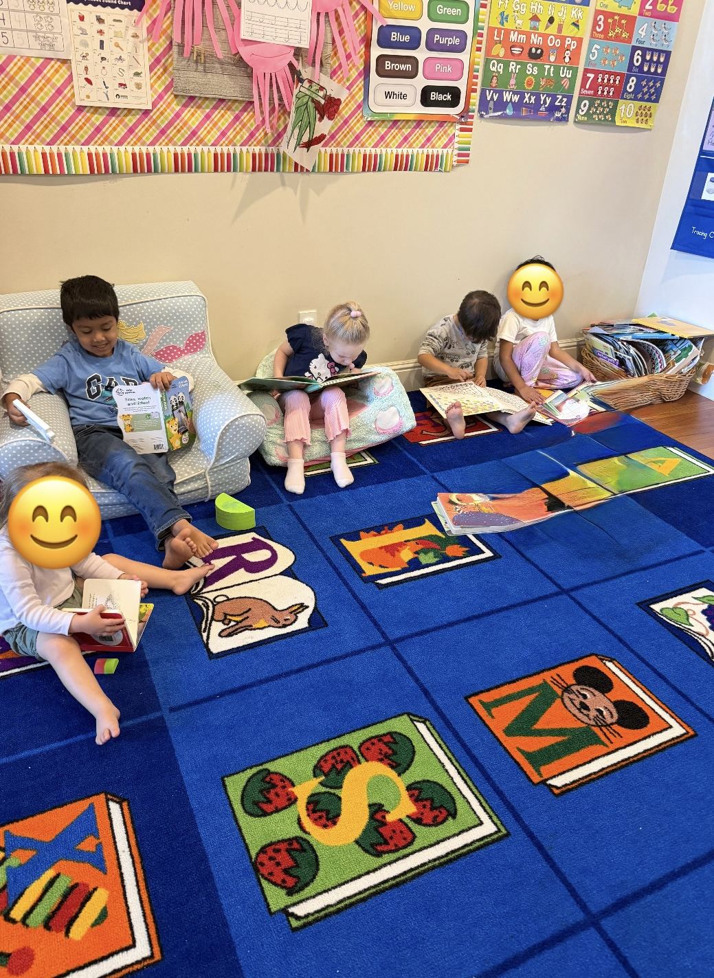 Five children reading picture books in the reading corner on an alphabet rug