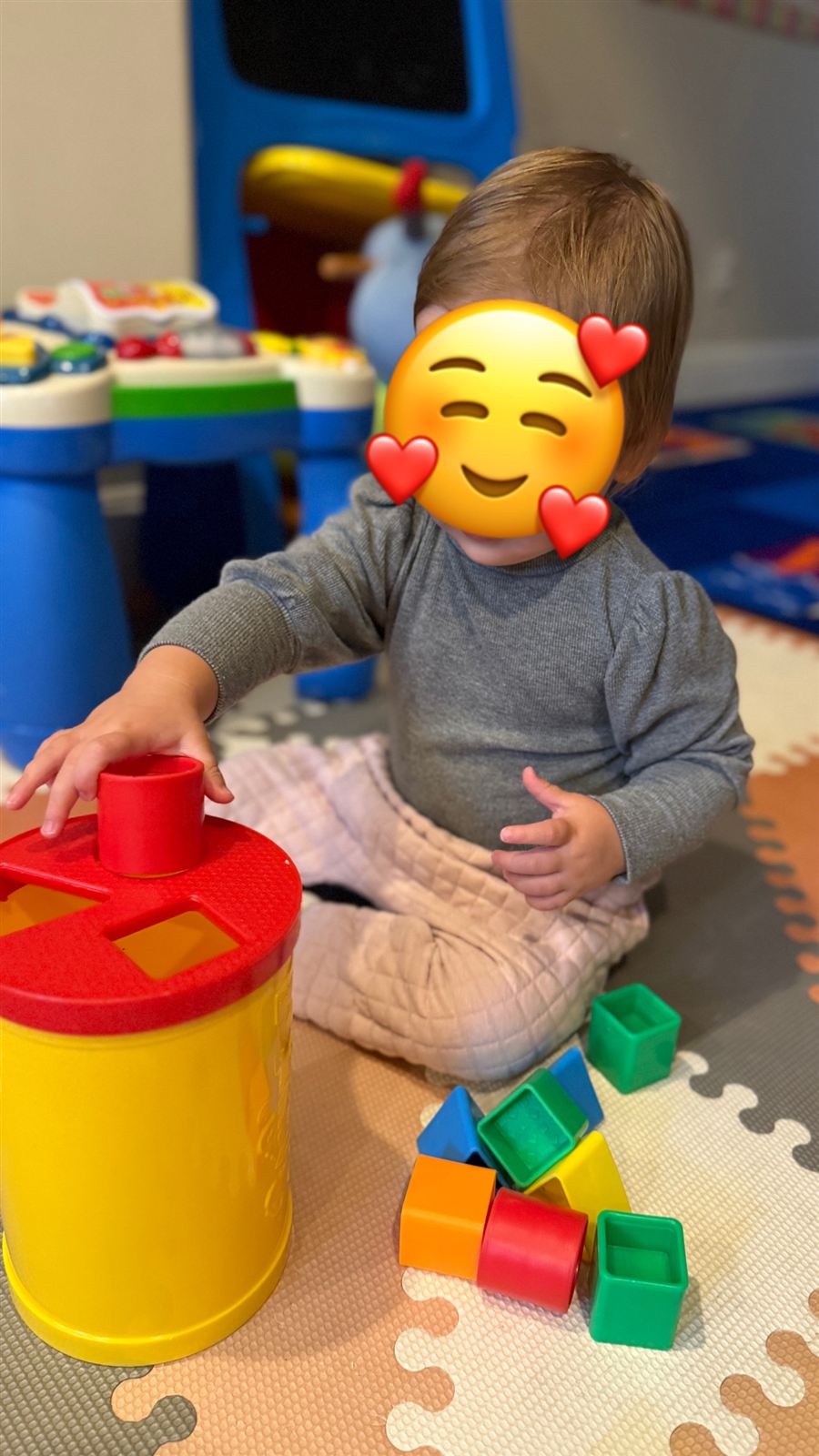 A young toddler fitting shapes into a shape sorter in the playroom